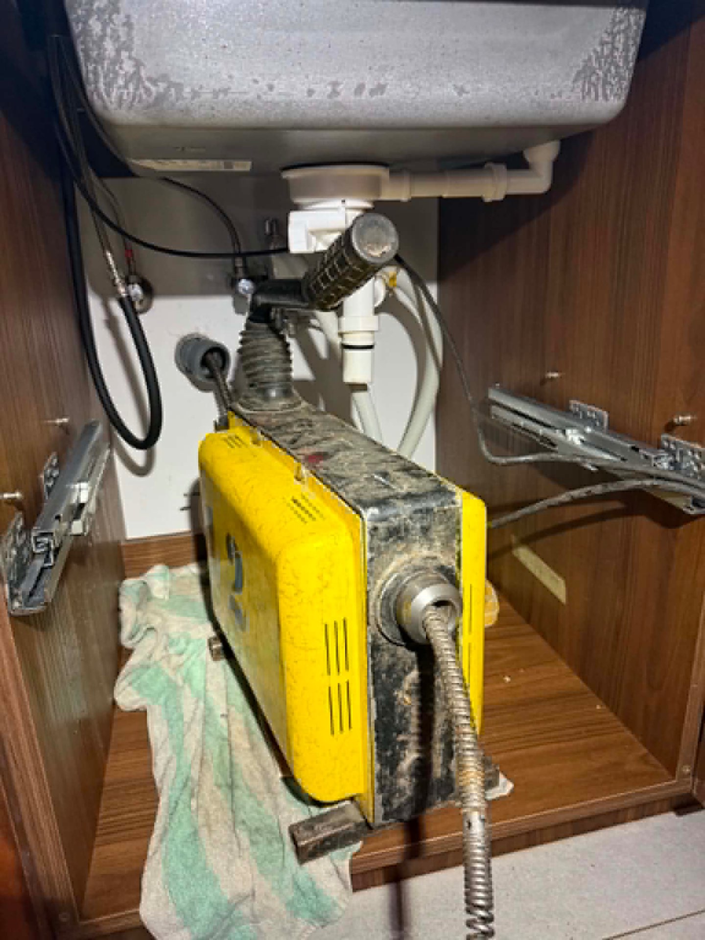High-pressure drain cleaning machine in action under sink